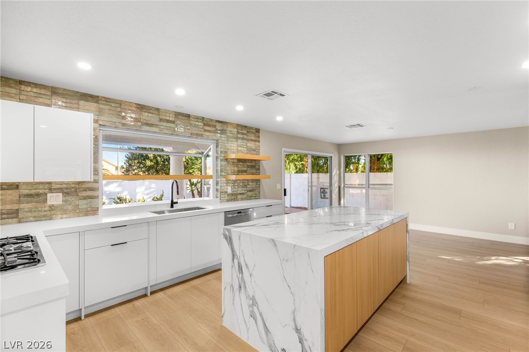 2104 Inverness Drive Henderson, NV 89074 - Photo 15 of 51 Kitchen featuring modern cabinets, white cabinets, a kitchen island, decorative backsplash, and recessed lighting