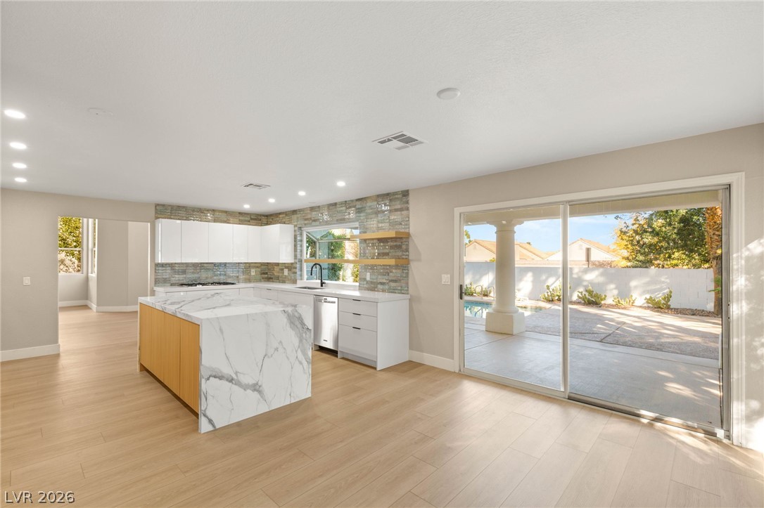 2104 Inverness Drive Henderson, NV 89074 - Photo 17 of 51 Kitchen featuring white cabinets, tasteful backsplash, modern cabinets, a kitchen island, and light stone counters