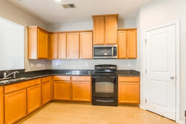 a kitchen with stainless steel appliances granite countertop a stove a sink and a microwave