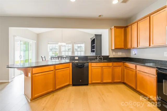 a large kitchen with stainless steel appliances granite countertop a sink a stove cabinets counter space and a window