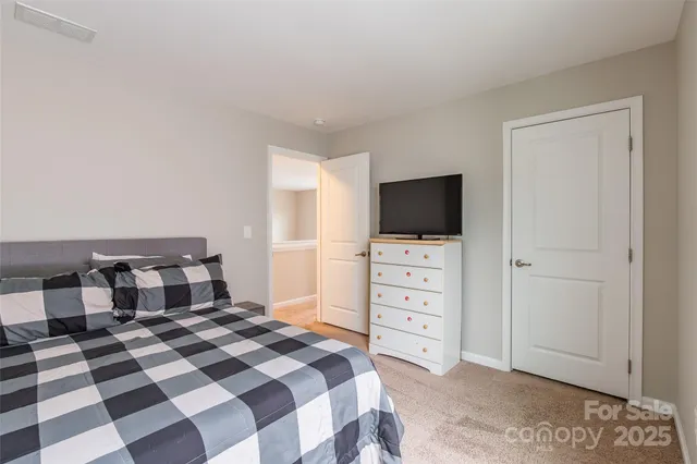 a bedroom with a bed and a flat tv screen on wall