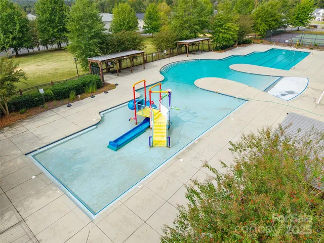 an aerial view of a house with swimming pool and large trees