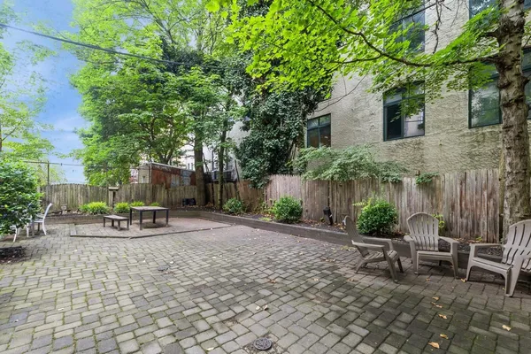 a view of a patio with table and chairs potted plants and large tree