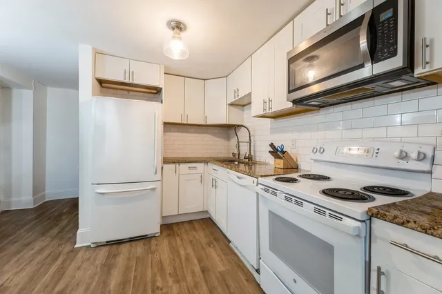 a kitchen with granite countertop cabinets stainless steel appliances and wooden floor