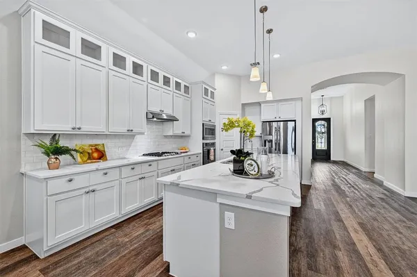a kitchen that has a lot of cabinets in it and wooden floors
