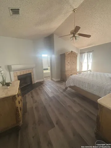 a view of a livingroom with a fireplace a ceiling fan and a window