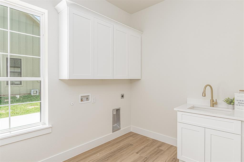 360 Dalton Road Canton, TX 75103 - Photo 20 of 33 Laundry room featuring white cabinetry, a built-in sink with a gooseneck faucet, wood-finish flooring, and a large window