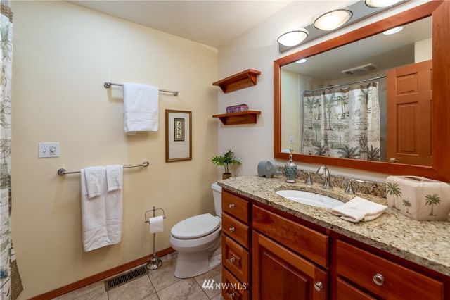 a bathroom with a granite countertop toilet sink and mirror