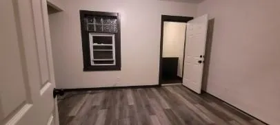 a view of a hallway with wooden floor and a window
