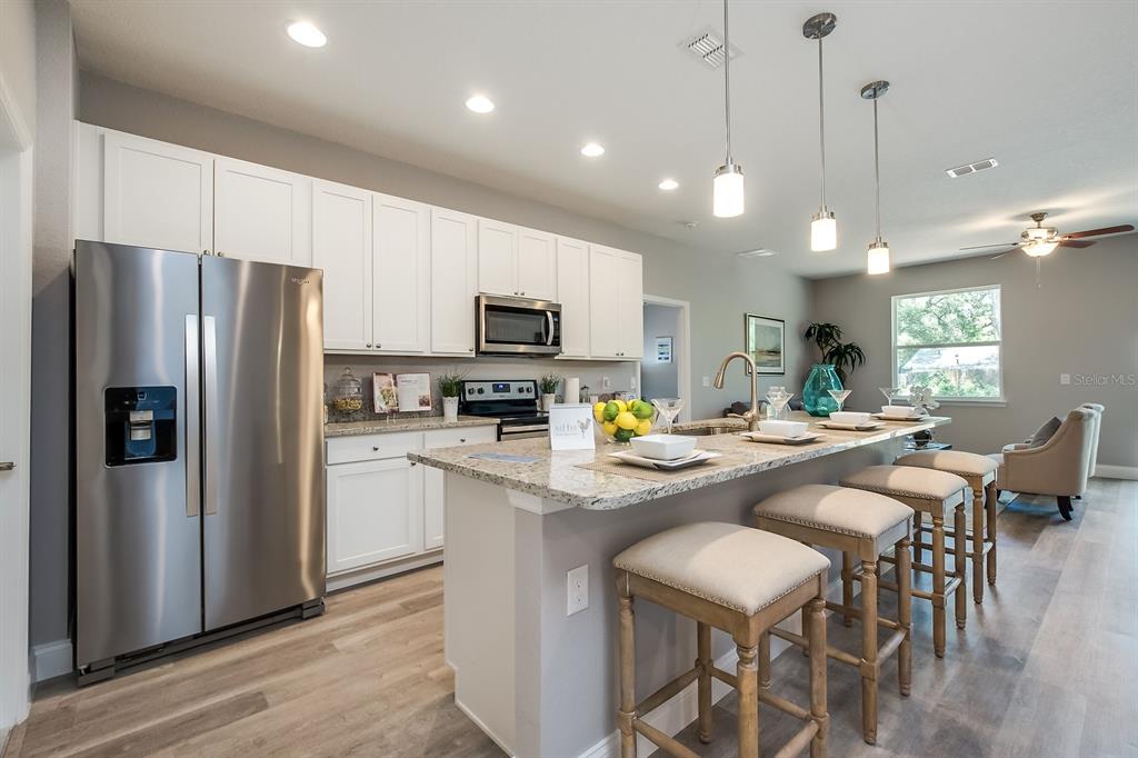 621 Paddock Street Orlando, FL 32833 - Photo 5 of 25 a kitchen with stainless steel appliances granite countertop a refrigerator a stove a sink a dining table and chairs with wooden floor