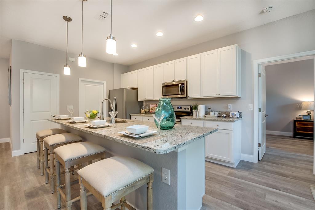 621 Paddock Street Orlando, FL 32833 - Photo 9 of 25 a kitchen with kitchen island granite countertop a stove a sink a refrigerator and white cabinets with wooden floor