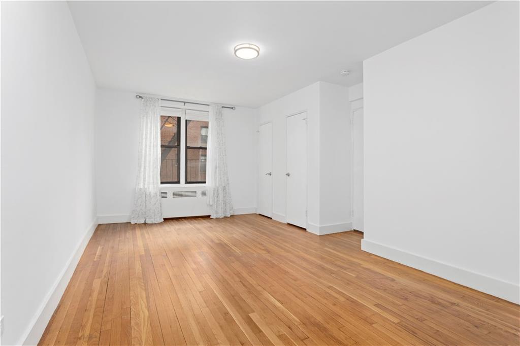 9511 Shore Road, Unit 101 Brooklyn, NY 11209 - Photo 5 of 8 an empty room with wooden floor and windows