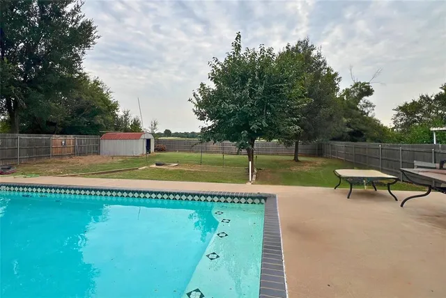a view of a swimming pool with a bench and trees around