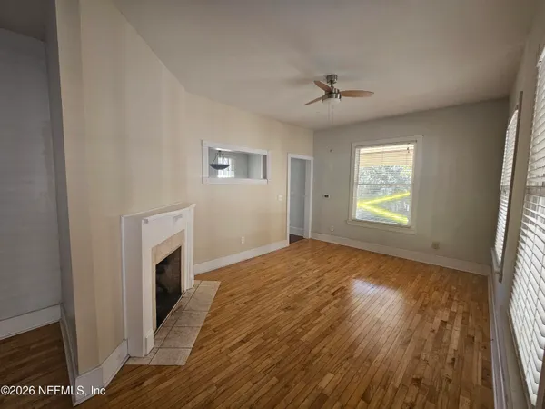 a view of empty room with a fireplace and wooden floor