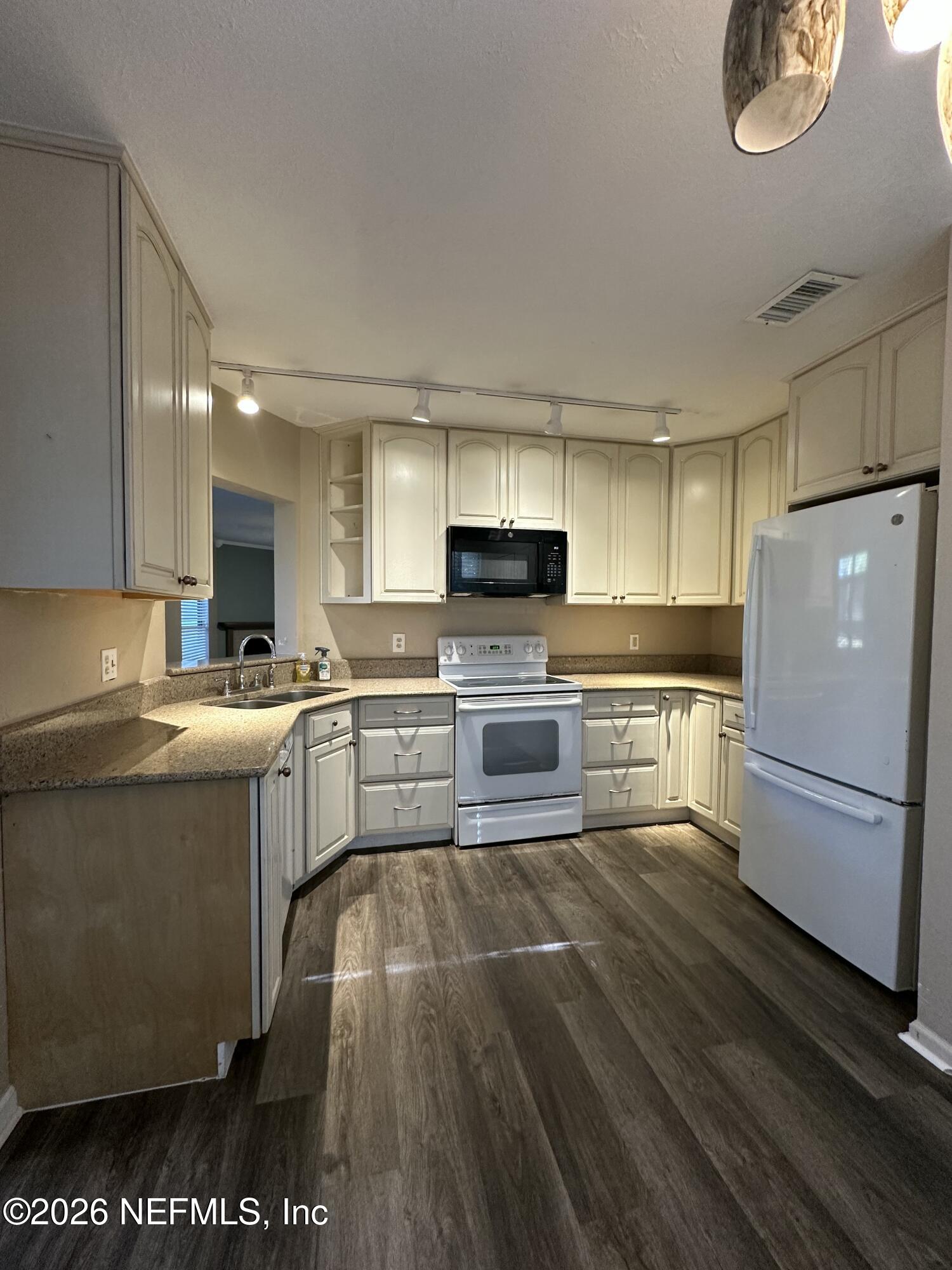 3801 Crown Point Road, Unit 3081 Jacksonville, FL 32257 - Photo 5 of 34 a kitchen with a refrigerator a stove top oven a sink dishwasher and white cabinets with wooden floor