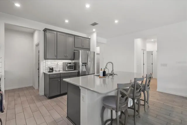 a large kitchen with sink a refrigerator and chairs