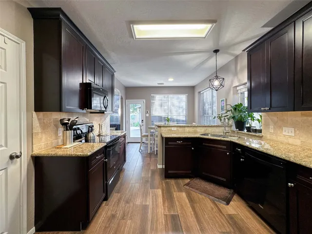 a large kitchen with stainless steel appliances granite countertop a sink dishwasher stove and oven