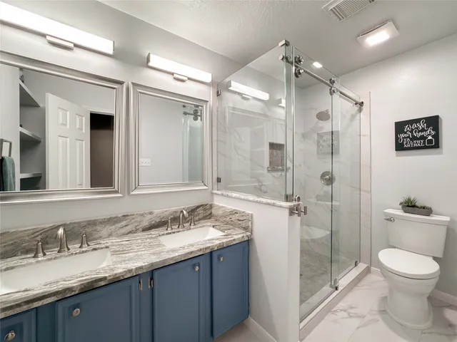 a bathroom with a granite countertop sink toilet a large mirror and shower