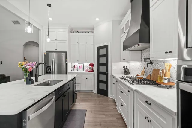 a kitchen with stainless steel appliances kitchen island granite countertop a sink stove and refrigerator