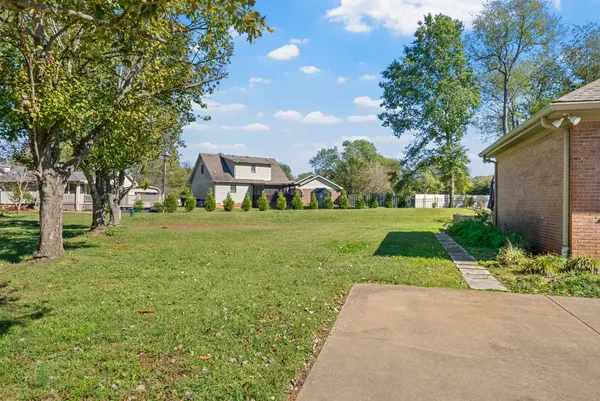 a view of a brick house next to a yard with big trees