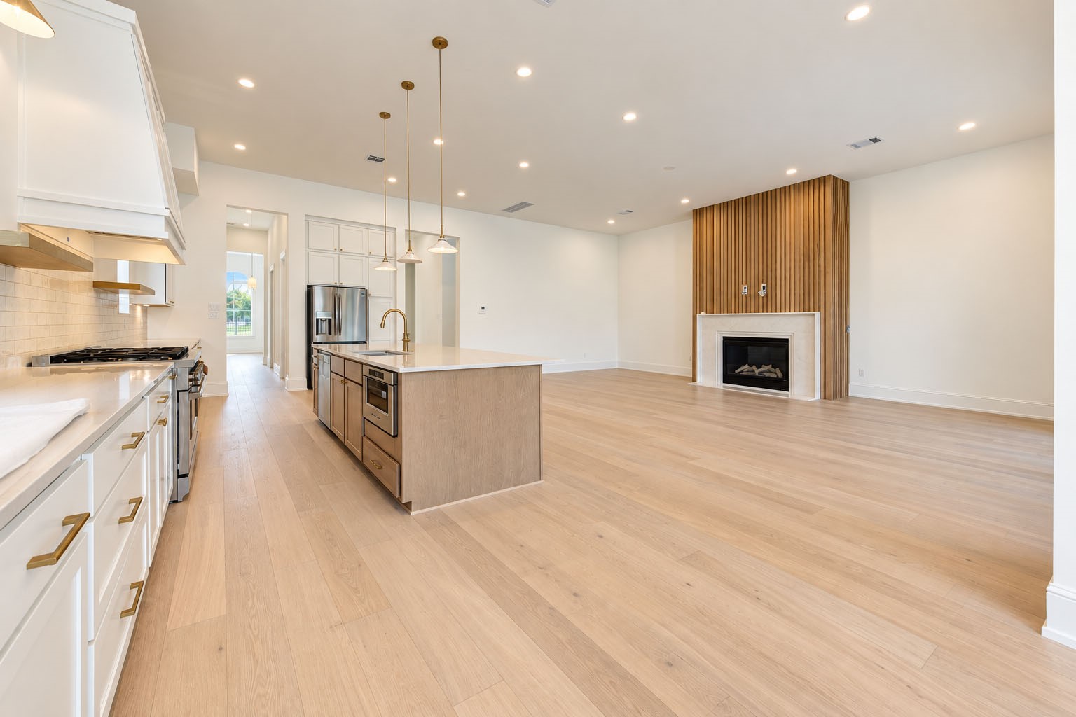 2309 Hollister Road Houston, TX 77080 - Photo 4 of 47 Expansive open-concept kitchen and living area blends refined modern design with effortless everyday luxury. The oversized waterfall-style island anchors the space, complemented by sleek cabinetry, premium appliances, wide-plank flooring, and abundant recessed lighting. A contemporary fireplace creates a sophisticated focal point, while the seamless layout offers an inviting setting for relaxed evenings, stylish entertaining, and memorable gatherings.