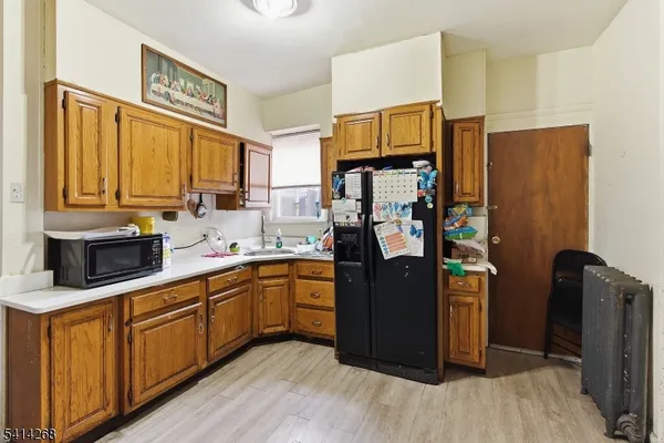 a kitchen with stainless steel appliances granite countertop a refrigerator a sink dishwasher and wooden cabinets with wooden floor