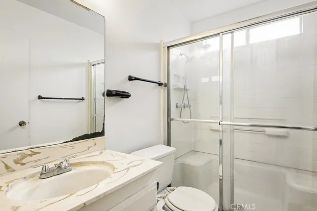 a bathroom with a granite countertop sink toilet and shower