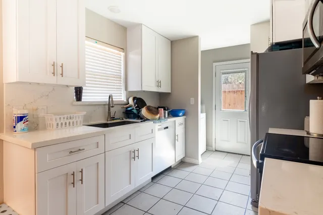 a kitchen with stainless steel appliances a white refrigerator a sink a window and cabinets