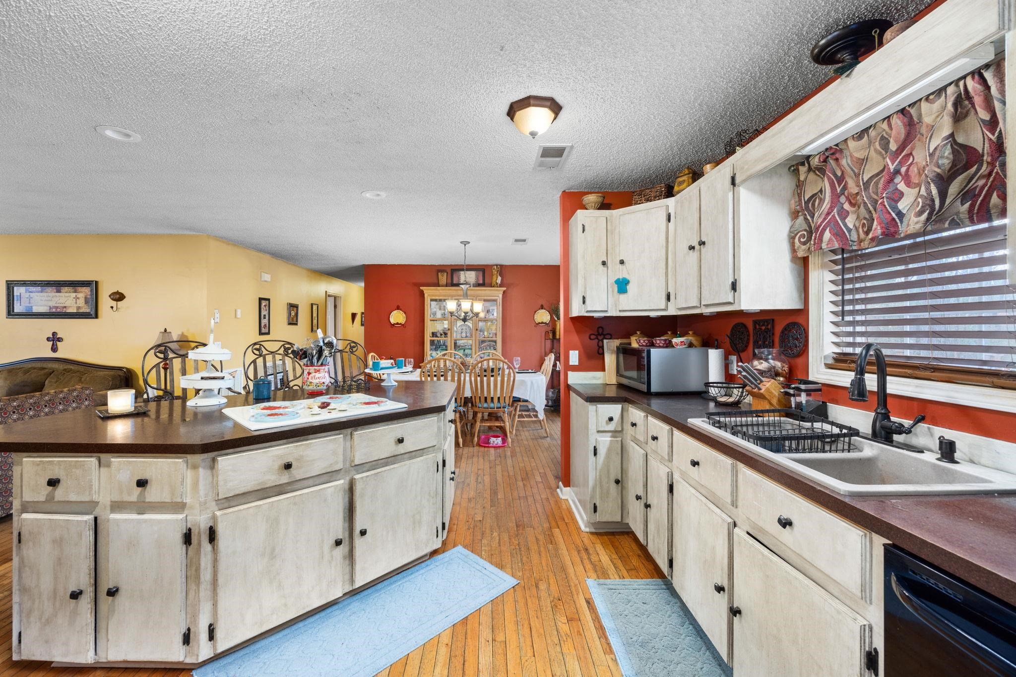 4625 Tucker Road Golden, MS 38847 - Photo 13 of 35 Kitchen with dark countertops, light wood-style floors, dishwasher, a textured ceiling, and stainless steel microwave