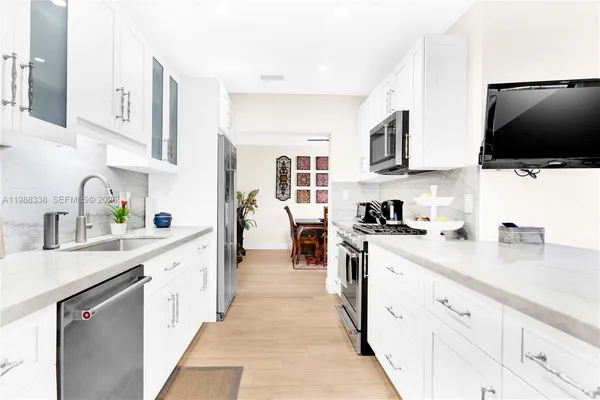 a kitchen with stainless steel appliances granite countertop a sink and dishwasher a stove top oven with white cabinets