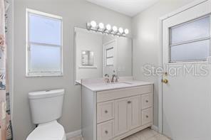 10446 Baylor Drive Spring Hill, FL 34608 - Photo 22 of 32 a bathroom with a toilet a sink and mirror