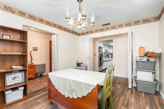 a dining room with wooden floor a chandelier a wooden table and chairs