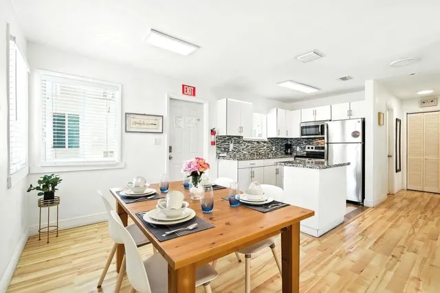 a kitchen with stainless steel appliances kitchen island granite countertop a refrigerator a stove a sink dishwasher and white cabinets with wooden floor