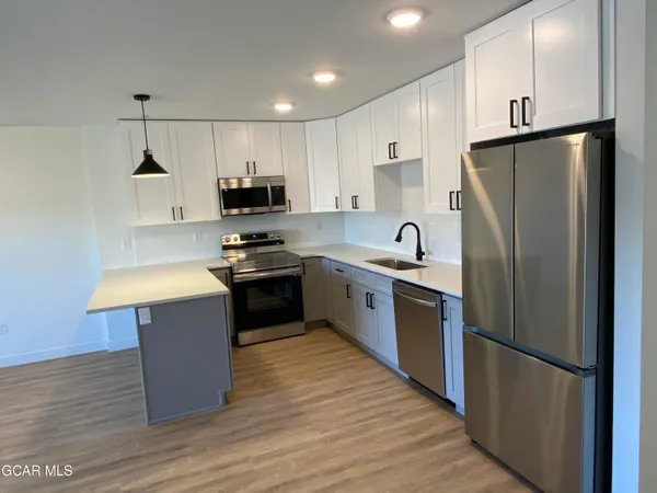 a kitchen with kitchen island granite countertop a refrigerator sink and cabinets