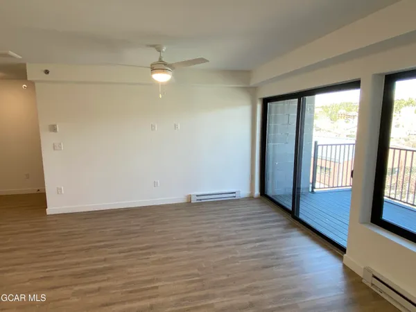 a view of an empty room with glass door and wooden floor