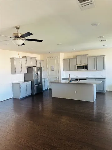 an open kitchen with wooden floor and chandelier
