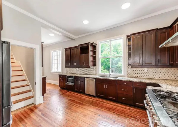 a kitchen with stainless steel appliances granite countertop wooden floors a stove and a sink