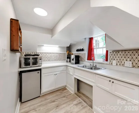 a kitchen with a sink dishwasher a stove and white cabinets