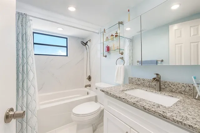 a bathroom with a granite countertop sink mirror toilet and bathtub