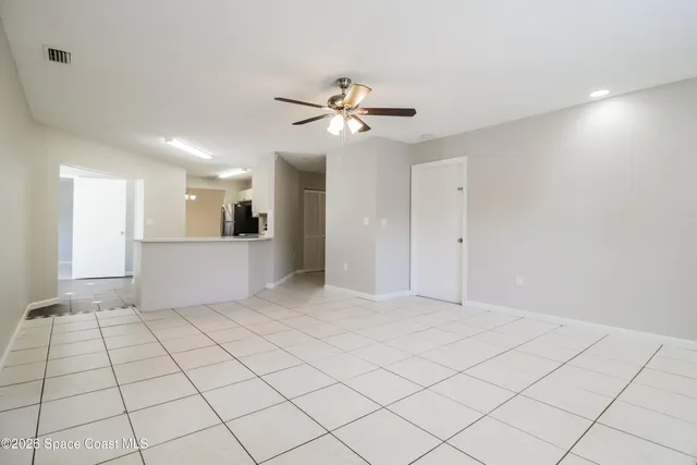 a view of an empty room and a kitchen chandelier fan