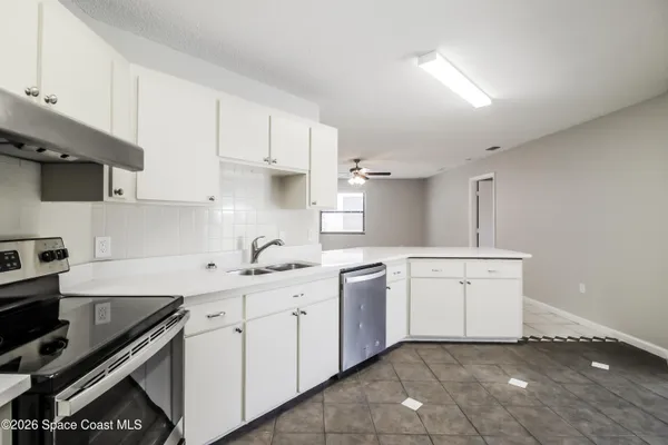 a kitchen with white cabinets a sink and appliances