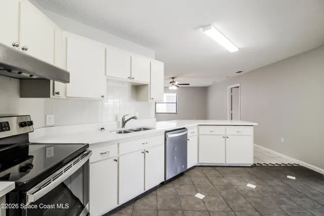 a kitchen with white cabinets a sink and appliances