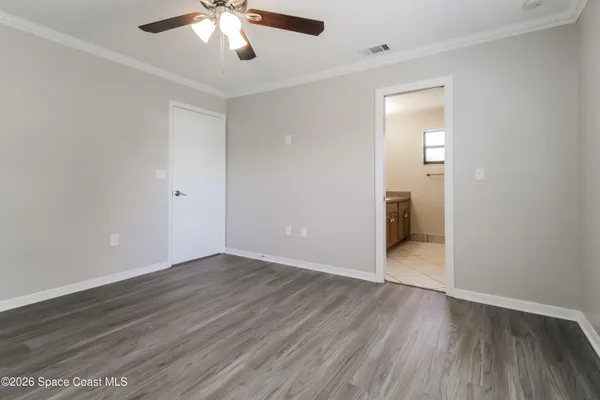 an empty room with wooden floor and a ceiling fan