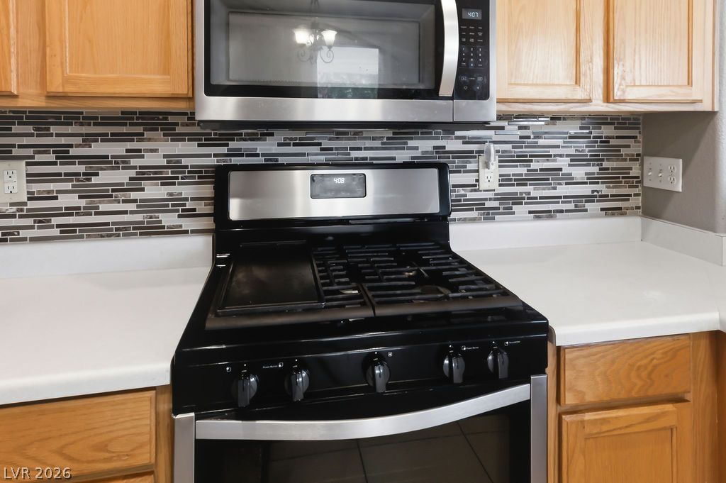 754 Solitude Point Avenue Henderson, NV 89012 - Photo 15 of 38 A well-appointed kitchen features a modern range, microwave, and stylish tile backsplash.