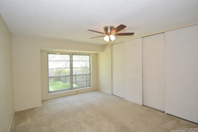 an empty room with windows and fan