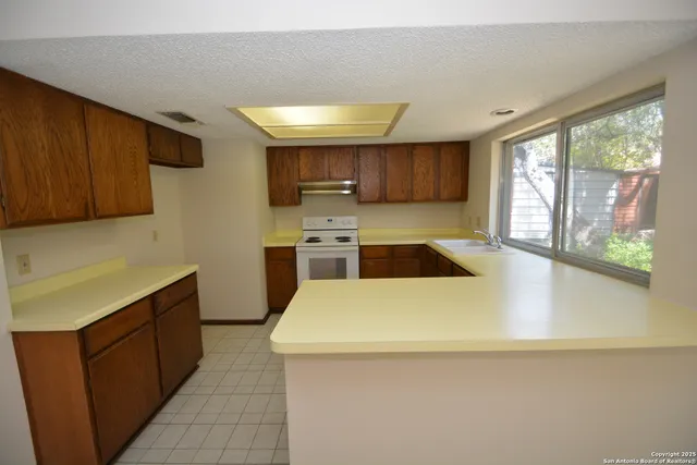 a kitchen with stainless steel appliances a large counter top a stove a sink and a refrigerator