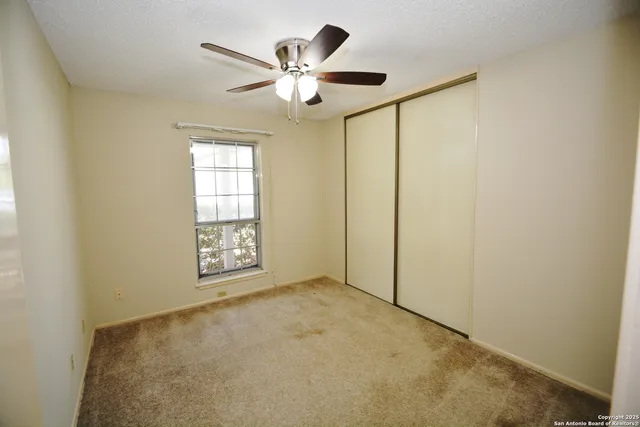 an empty room with windows and fan