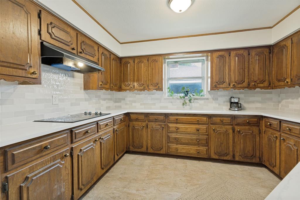 705 South Grove Road Richardson, TX 75081 - Photo 13 of 26 U-shaped kitchen featuring wood cabinetry, light-toned countertops, and a white subway tile backsplash