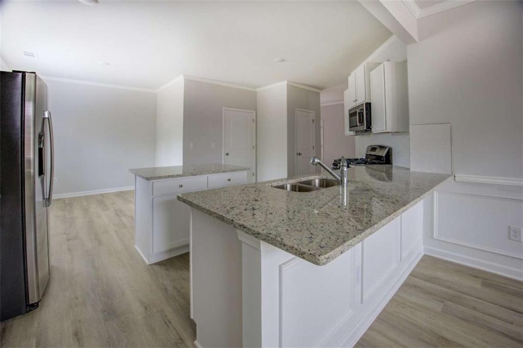 1007 Towne Circle Social Circle, GA 30025 - Photo 18 of 38 a kitchen with stainless steel appliances granite countertop a sink dishwasher and a refrigerator with wooden floor
