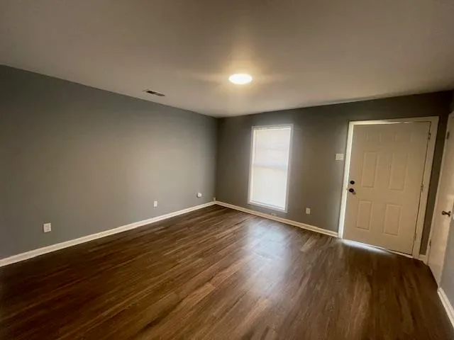 a view of an empty room with wooden floor and closet